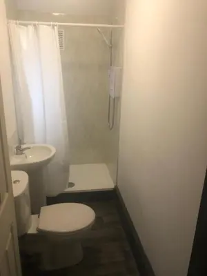 a bathroom with a toilet and a shower and a sink at Kirubash Central Pier Hotel in Blackpool