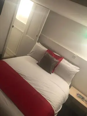 a bed with red and white pillows in a room at Kirubash Central Pier Hotel in Blackpool