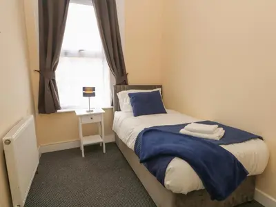 a bedroom with a bed with a blue blanket and a window at St Heliers in Blackpool