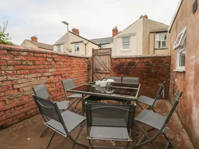 a patio with a table and chairs in front of a brick wall at St Heliers in Blackpool