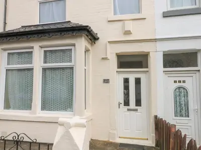 a house with a white door and a fence at St Heliers in Blackpool