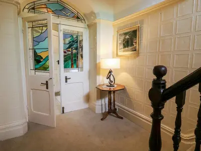 a hallway with a door and a table with a lamp at Manor House in Accrington