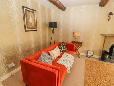 a living room with an orange couch and a fireplace at Clerk Beck Cottage in Ulverston