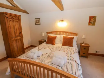 a bedroom with a large wooden bed with towels on it at Clerk Beck Cottage in Ulverston