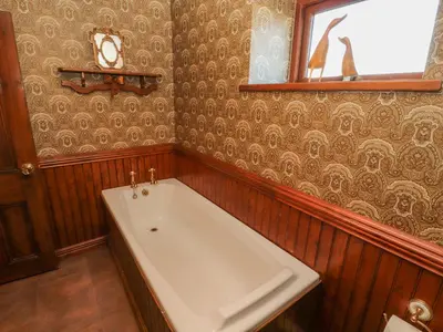 a large bath tub in a room with wooden walls at Clerk Beck Cottage in Ulverston