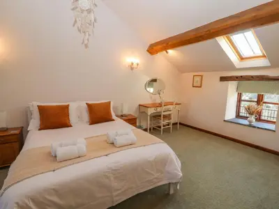 a bedroom with a large bed and a desk at Clerk Beck Cottage in Ulverston