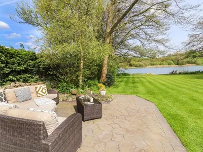 a patio with two wicker couches and a lawn at Clerk Beck Cottage in Ulverston