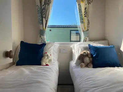 two stuffed animals sitting on two beds in a bedroom at 37 Bay View Oceans Edge by Waterside Holiday Lodges in Lancaster