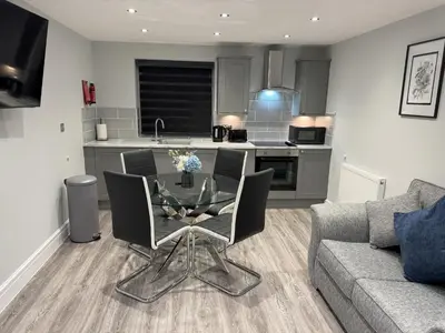 a living room with a glass table and a kitchen at Edward Place Luxury Hot Tub Apartments in Blackpool