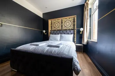 a bedroom with a bed with a black wall at Hollywood Suite Sasco Apartments in Blackpool