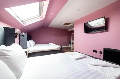 a bedroom with two beds and a tv on the wall at Hollywood Suite Sasco Apartments in Blackpool