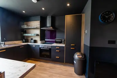 a kitchen with black walls and a clock on the wall at Hollywood Suite Sasco Apartments in Blackpool