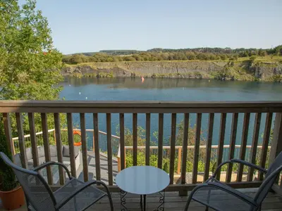a table and chairs on a balcony with a view of a river at Casa Loma in Carnforth