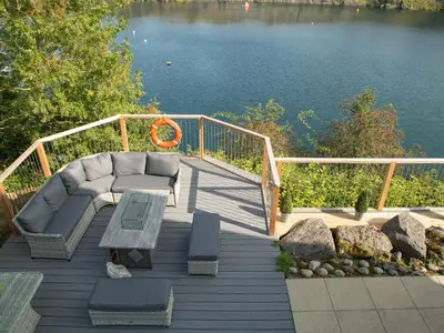 a deck with a couch and a table next to the water at Casa Loma in Carnforth