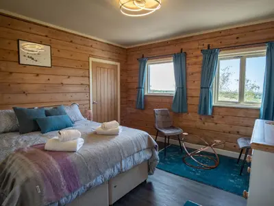 a bedroom with wooden walls and a bed and a chair at Casa Loma in Carnforth