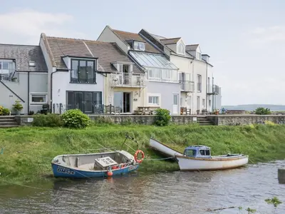 two boats on the water in front of a house at Lazey Cottage in Millom