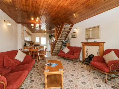 a living room with red couches and a wooden ceiling at Lazey Cottage in Millom