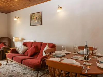 a living room with a red couch and a table at Lazey Cottage in Millom