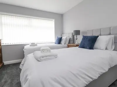 a bedroom with two beds with white sheets and blue pillows at 23 Ryden Avenue in Cleveleys