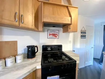 a kitchen with a stove and wooden cabinets at Elletson Park Wood fired Hot tubs, Caravans & Pods in Preston