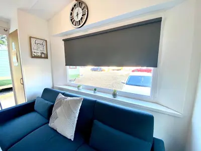 a blue couch in a living room with a large window at Elletson Park Wood fired Hot tubs, Caravans & Pods in Preston