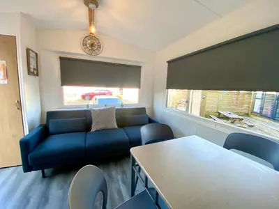 a living room with a blue couch and a table at Elletson Park Wood fired Hot tubs, Caravans & Pods in Preston