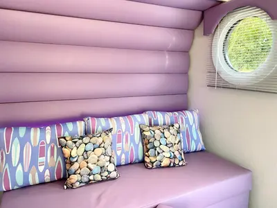a purple couch with pillows next to a window at Elletson Park Wood fired Hot tubs, Caravans & Pods in Preston