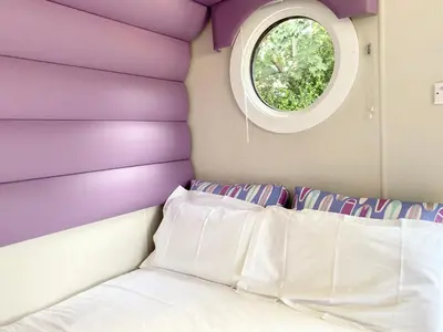 a bedroom with a purple headboard and a window at Elletson Park Wood fired Hot tubs, Caravans & Pods in Preston