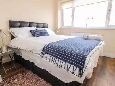 a bed with a blue and white comforter and a window at The Beach House in Cleveleys