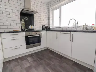 a kitchen with white cabinets and a sink at The Beach House in Cleveleys