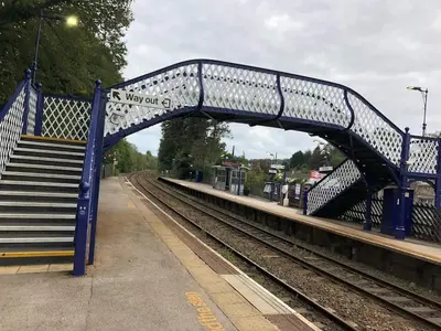 a blue bridge at a train station with stairs at Milo’s Retreat in Arnside
