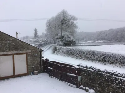 a snow covered yard with a house and a road at Milo’s Retreat in Arnside