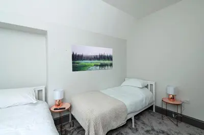 two beds in a white room with two lamps at North Lodge in Lancaster