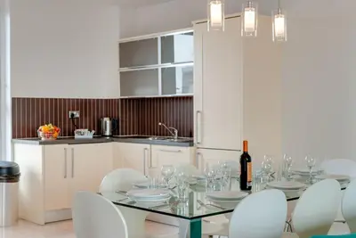 a dining room with a glass table and white chairs at Base Serviced Apartments - Duke Street in Liverpool