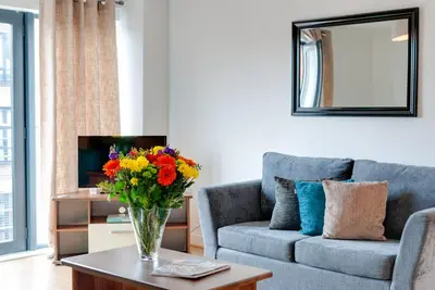 a living room with a couch and a vase of flowers on a table at Base Serviced Apartments - Duke Street in Liverpool