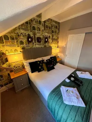 a bedroom with a large bed and a desk with a bed sidx sidx at Delovely Hotel in Blackpool