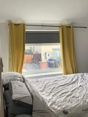a bed in front of a window with yellow curtains at Beautiful house in a perfect location in Saint Annes on the Sea