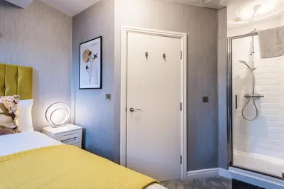 a bedroom with a yellow bed and a shower at Host & Stay - The Pilgrim Coach Houses in Liverpool