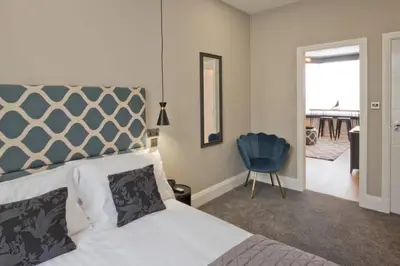 a bedroom with a bed and a blue chair at BlackBird Luxury Accommodation Room 6 in Blackpool