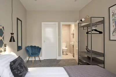 a bedroom with a bed and a blue chair at BlackBird Luxury Accommodation Room 6 in Blackpool