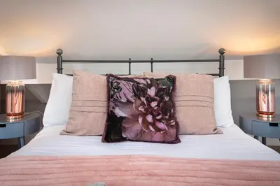 a bedroom with a bed with pink sheets and pillows at Cottage - Sleeps4 - PetFriendly - Garden - ByBeach in Saint Annes on the Sea