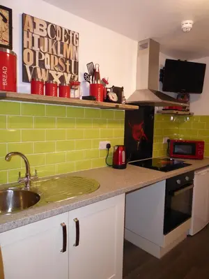 a kitchen with a sink and a counter with green tiles at The Myriad in Preston