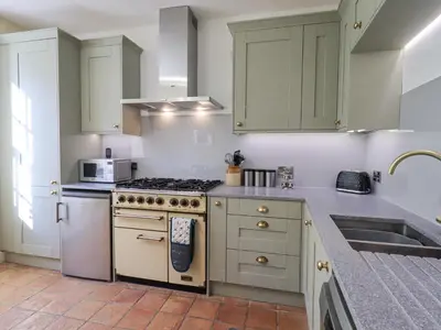 a kitchen with green cabinets and a stove top oven at Westmorland Cottage in Grange Over Sands