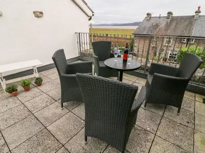 a patio with chairs and a table with a bottle of wine at Westmorland Cottage in Grange Over Sands
