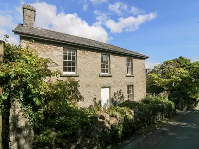 an old brick house with a stone wall at Westmorland Cottage in Grange Over Sands