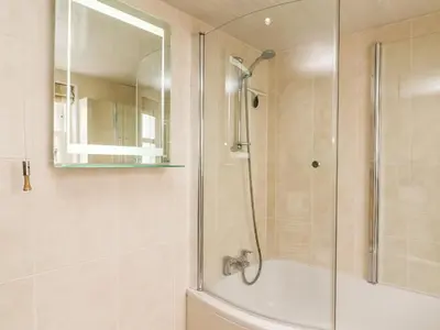 a bathroom with a shower and a tub and a sink at Westmorland Cottage in Grange Over Sands