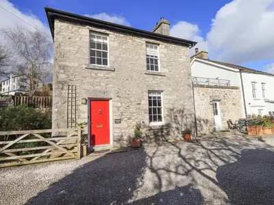 an old stone house with a red door at Westmorland Cottage in Grange Over Sands