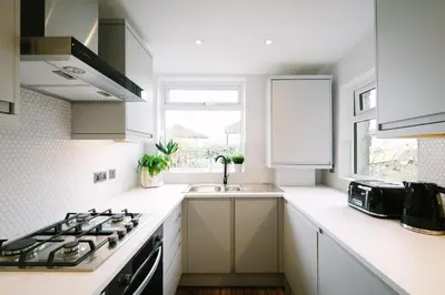 a white kitchen with a sink and a stove at Period Retreat for 6, explore the Lake District in Lancaster