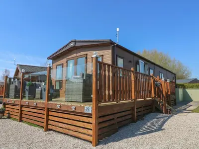a large wooden house with a large deck at Lancaster Lodge in Carnforth