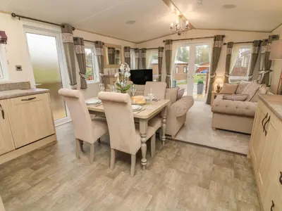 a kitchen and living room of a caravan with a table and chairs at Lancaster Lodge in Carnforth